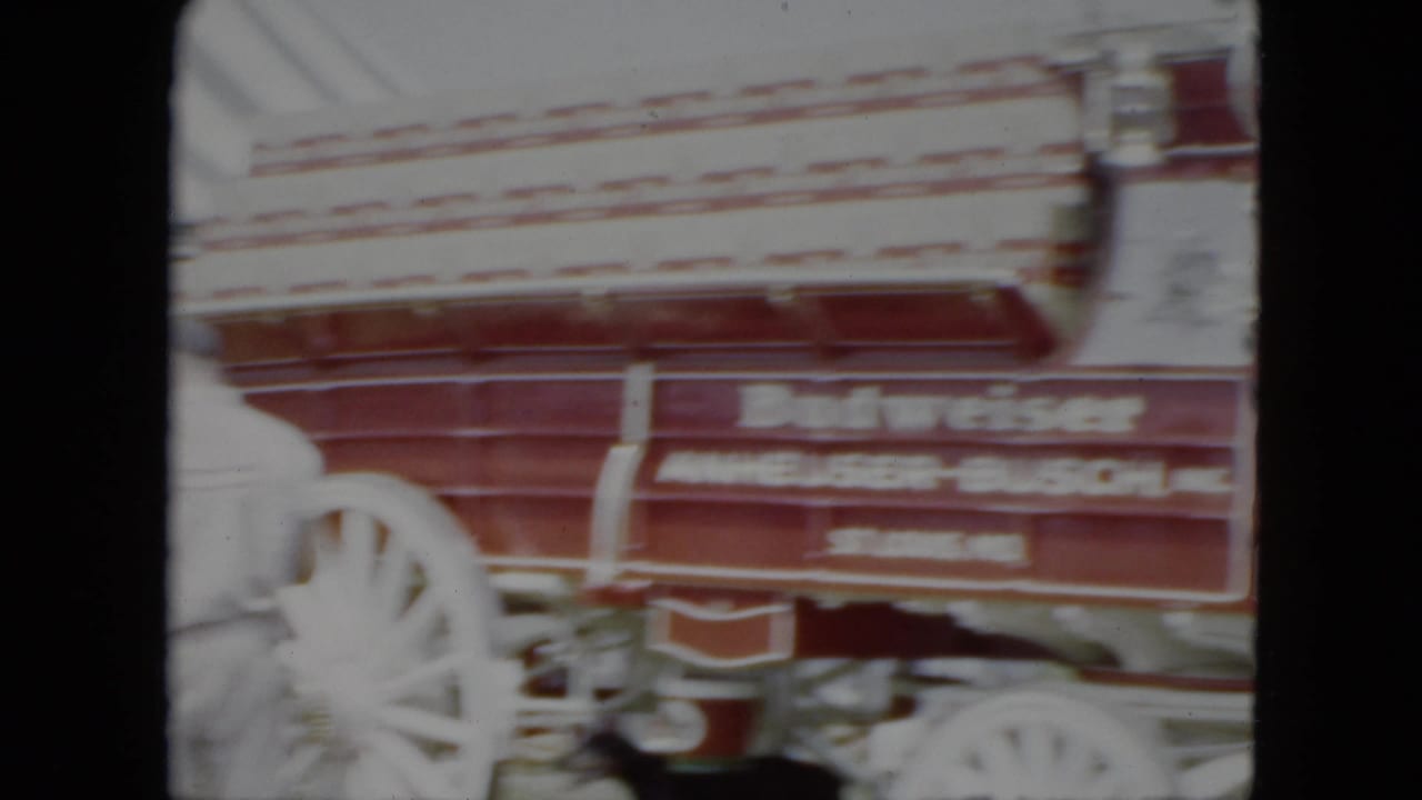 Red stagecoach with white wooden wheels and white lettering fills the frame edge.