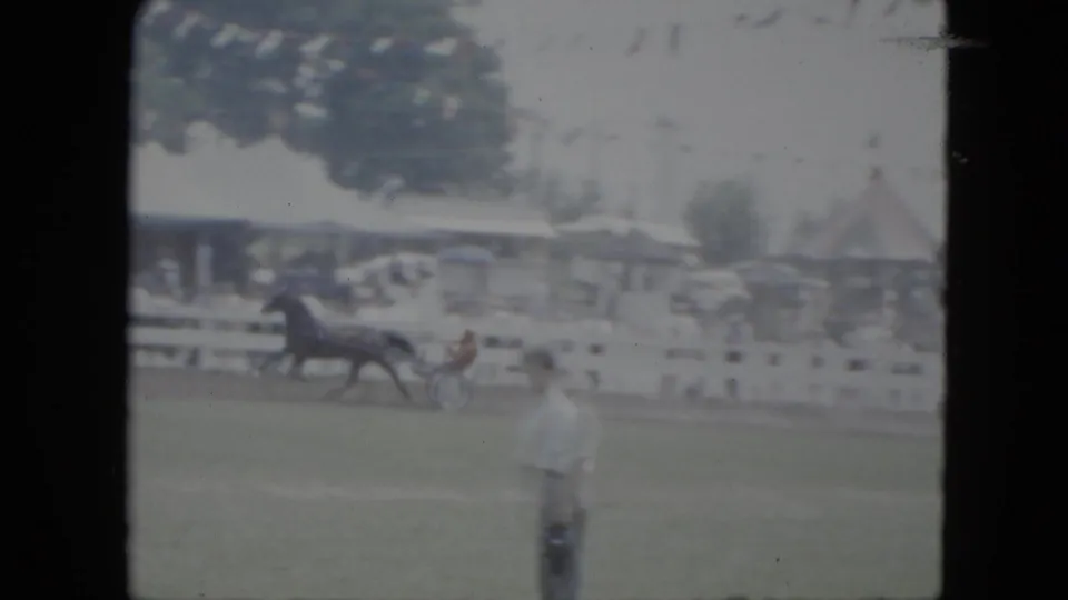 1951 Cleveland fairground view with a horse-drawn sulky or small cart, spectators behind a rail, and a foreground bystander.
