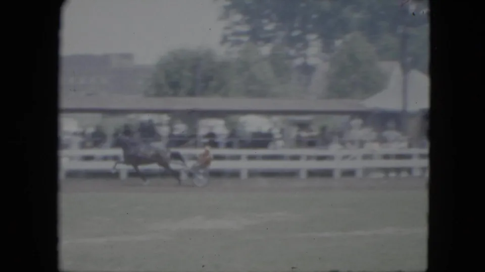 1951 Cleveland 8mm frame showing a horse pulling a small racing cart across grass before a white fence and crowded stands.
