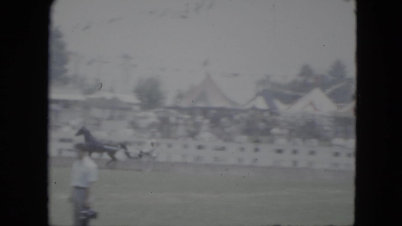 1951 Cleveland frame showing a horse and sulky on a grassy track while a man in a light shirt stands near the foreground.