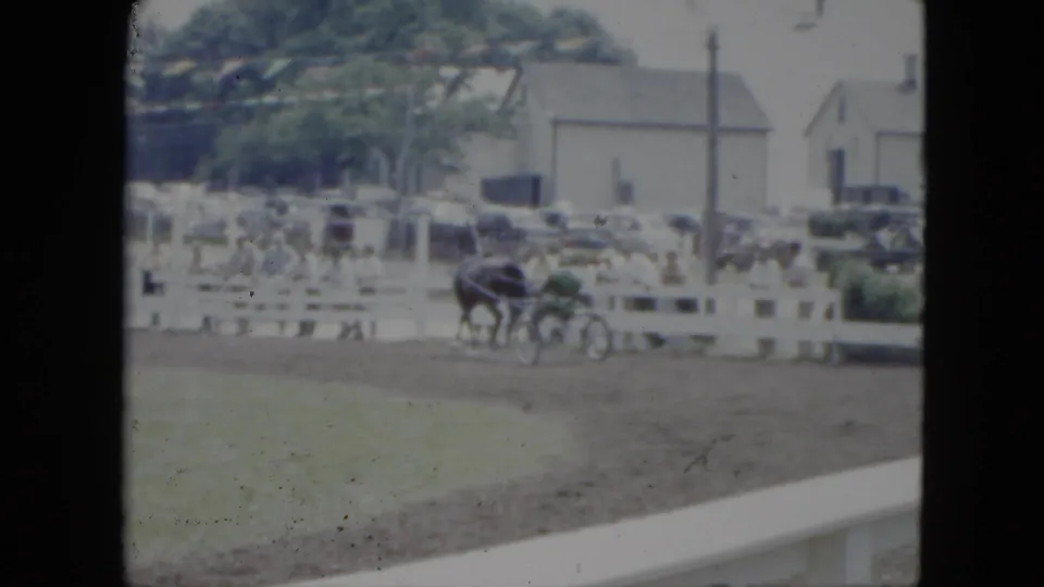 The final frame shows the chaise cart near the white fence, with spectators, trees, parked cars, and buildings behind the Cleveland track.
