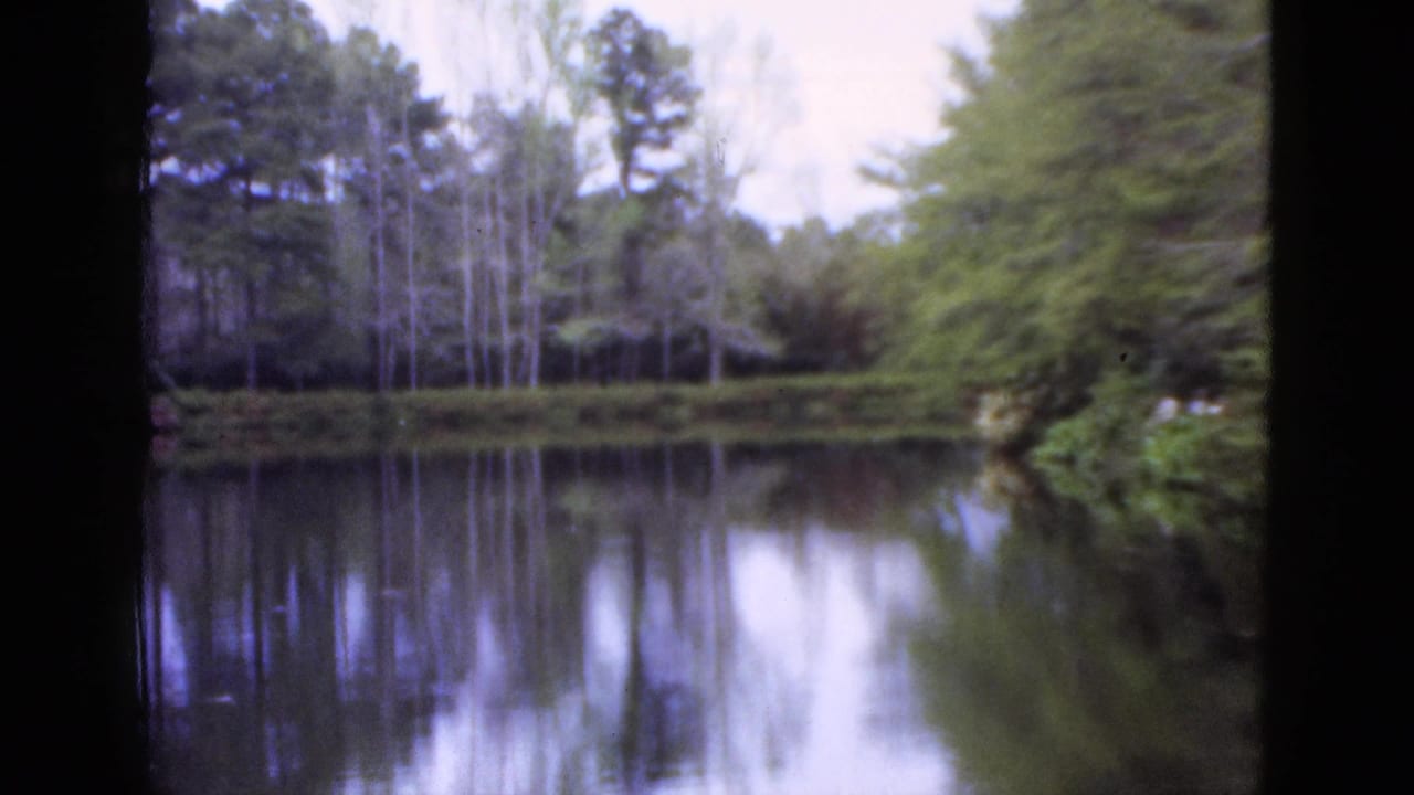 1952 Florida 8mm frame showing a still lake with tree reflections and dark framing along the sides.
