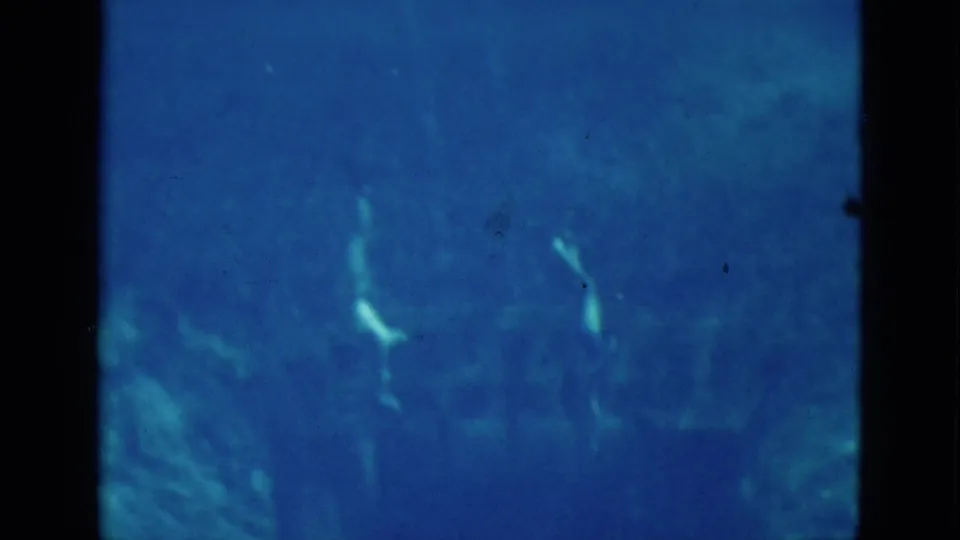 1952 Florida underwater home-movie frame showing swimmers partly visible in blue water with soft focus and grain.