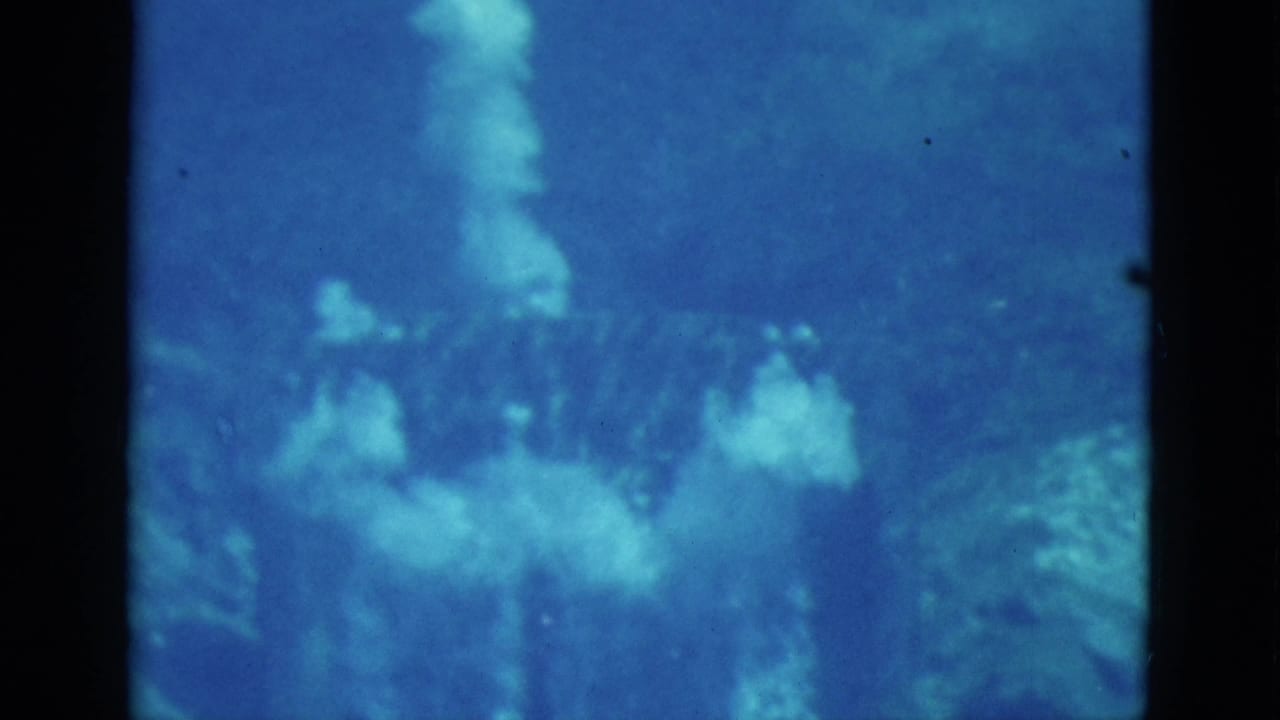 1952 Florida 8mm underwater footage showing blue water, bubbles, and indistinct rock or reef shapes with a faint swimmer form.