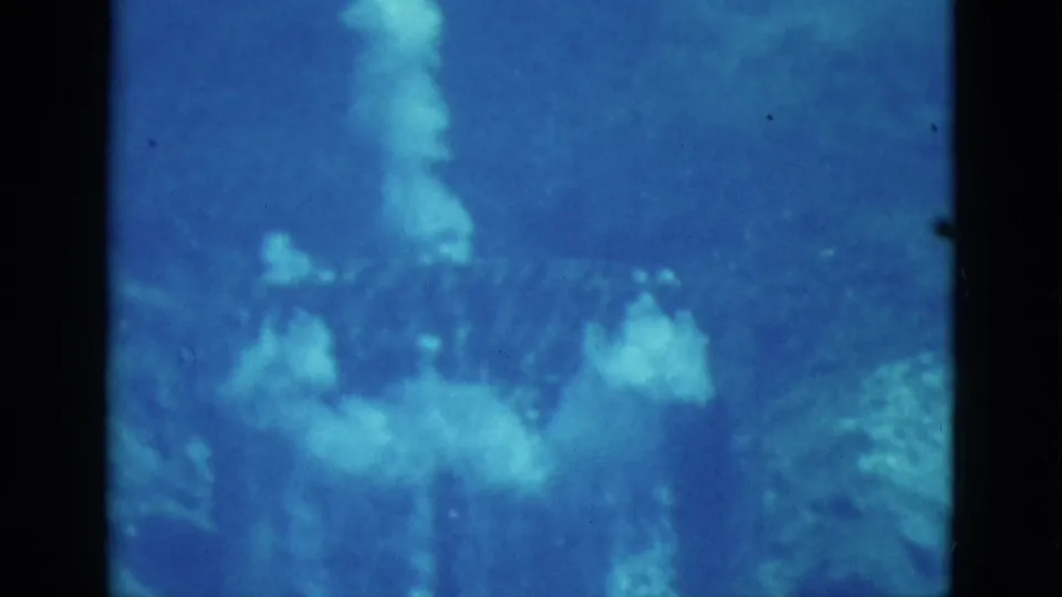 1952 Florida 8mm underwater footage showing blue water, bubbles, and indistinct rock or reef shapes with a faint swimmer form.