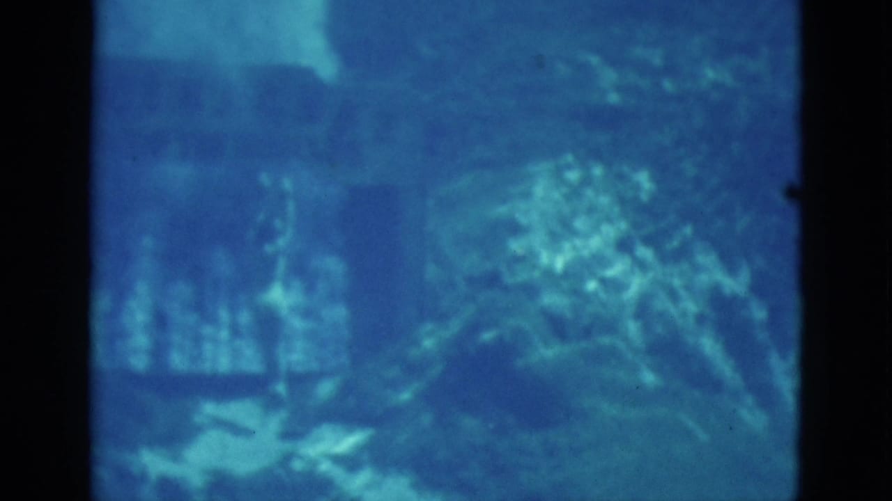 Underwater view with a swimmer near rocks and suspended bubbles.