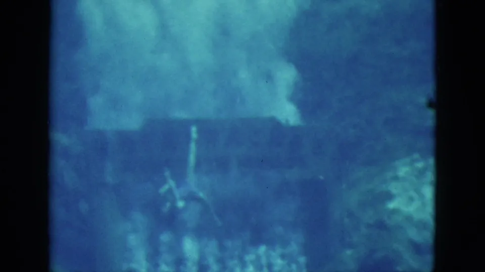 1952 Florida home-movie still with a swimmer low in the blue underwater frame, partly obscured by haze and refraction.