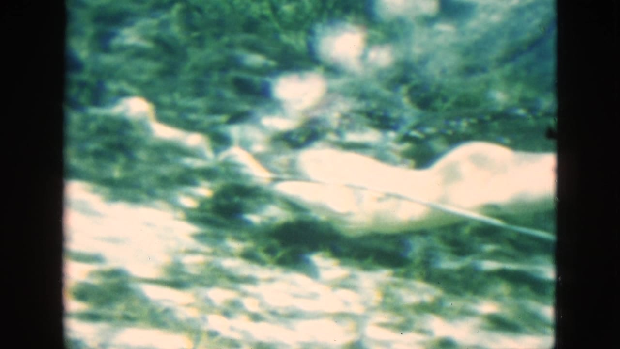 Swimmer stretched out underwater with bright glare, bubbles, and a snorkel tube visible.