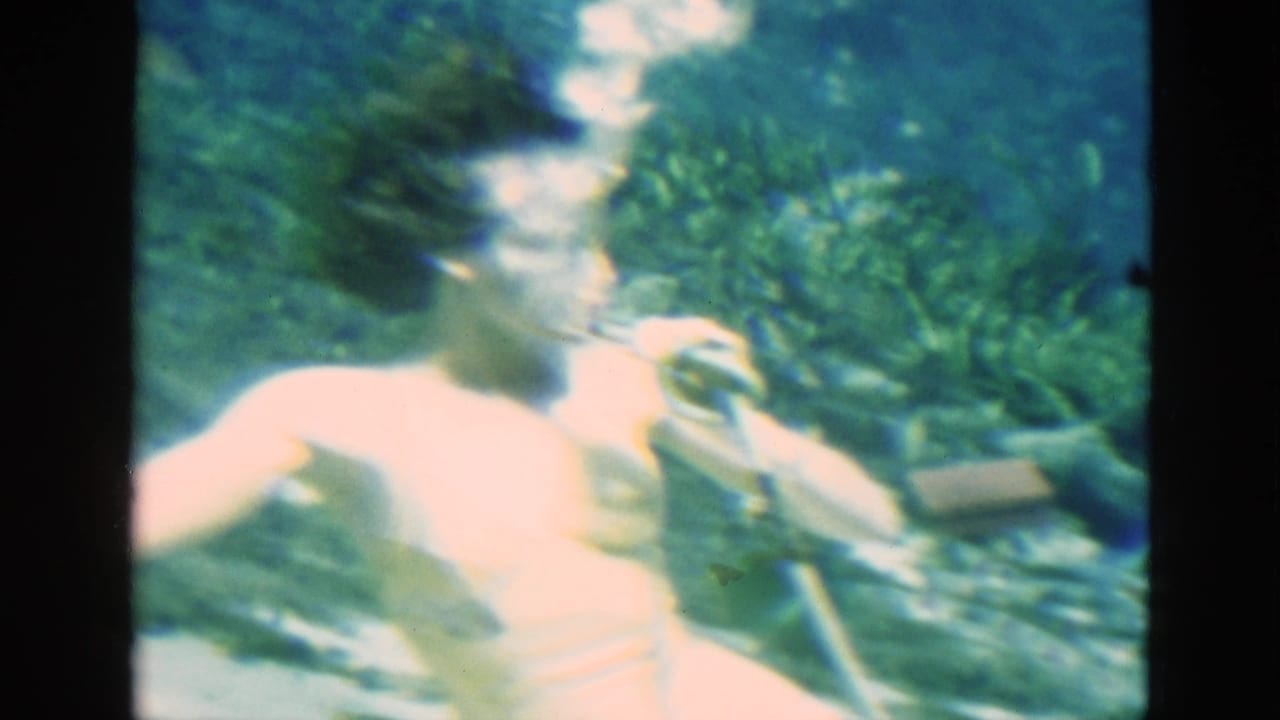 Underwater swimmer turns with bubbles rising near her face and tube.