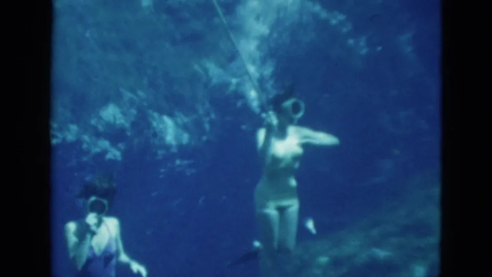 1952 Florida 8mm frame showing two women underwater with goggles and breathing tubes in clear blue-green water.