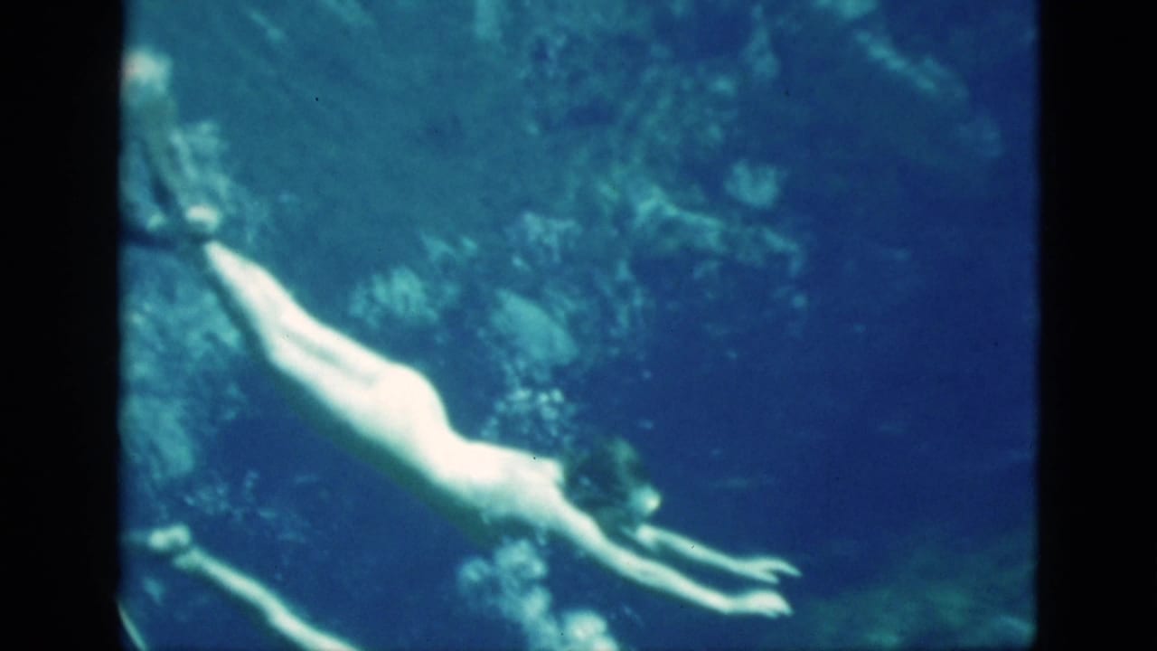 Woman in a swimsuit and fins swims underwater through blue water.