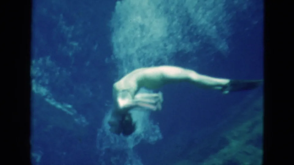 1952 Florida 8mm frame showing a woman curling underwater near bubbles, with another swimmer partly visible beneath her.