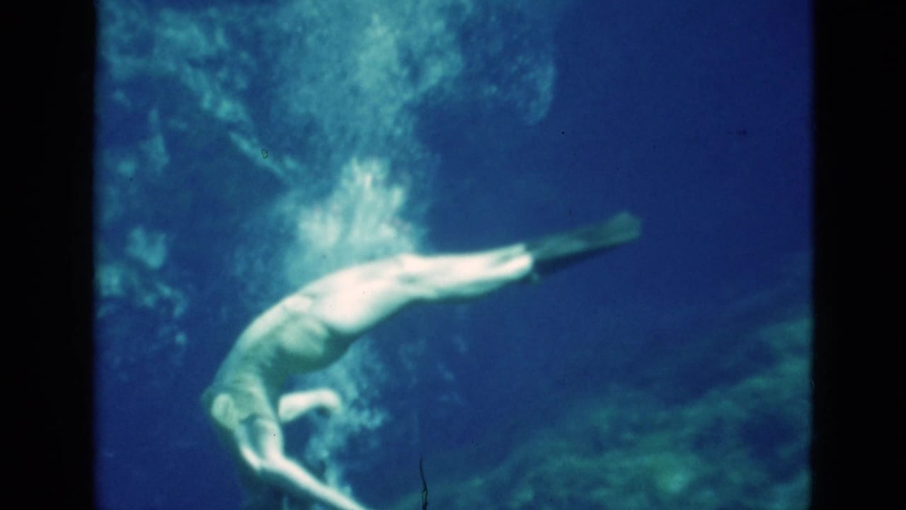 Woman swims horizontally underwater with fins extended and bubbles trailing upward.