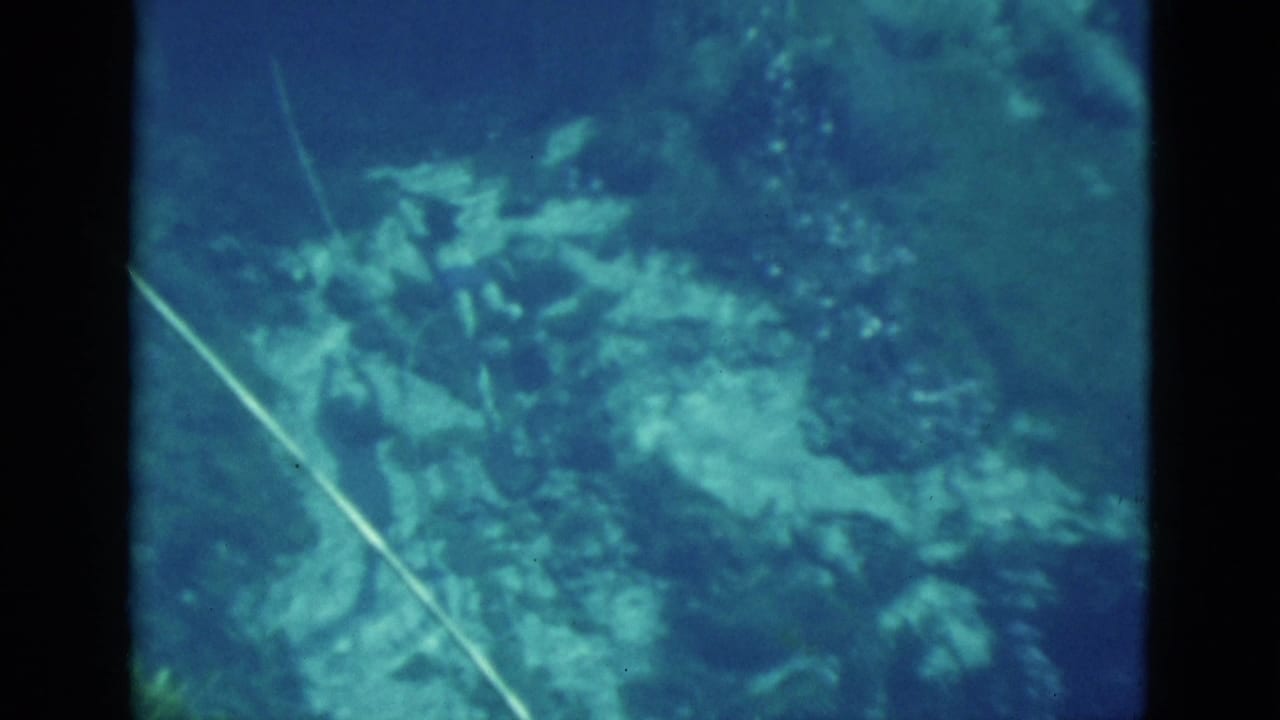 1952 Florida 8mm frame showing an underwater reef area with a visible hose line and blue-green home-movie color cast.