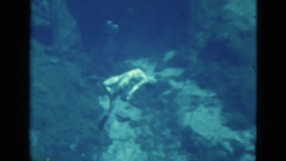 1952 Florida 8mm frame showing a female diver near reef and darker underwater formations at the end of the clip.