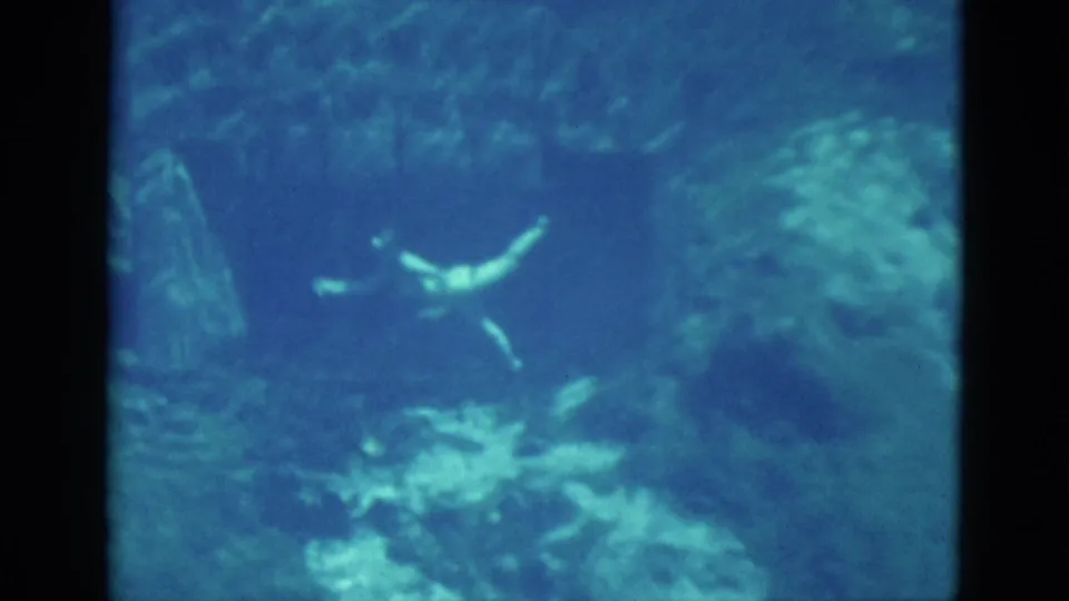 1952 Florida 8mm frame showing the swimmer with arms extended in a murky natural underwater setting.