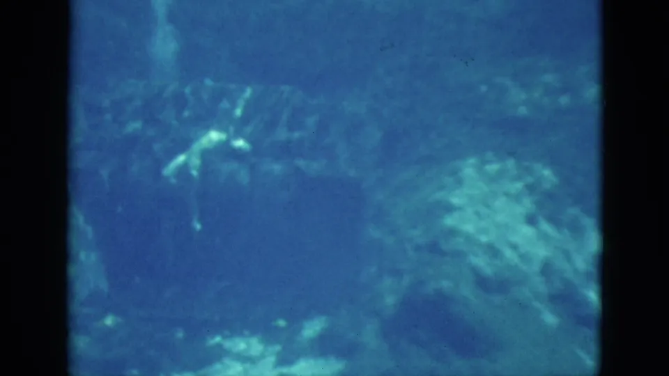1952 Florida underwater frame where the swimmer is partially obscured by haze and rocky formations.