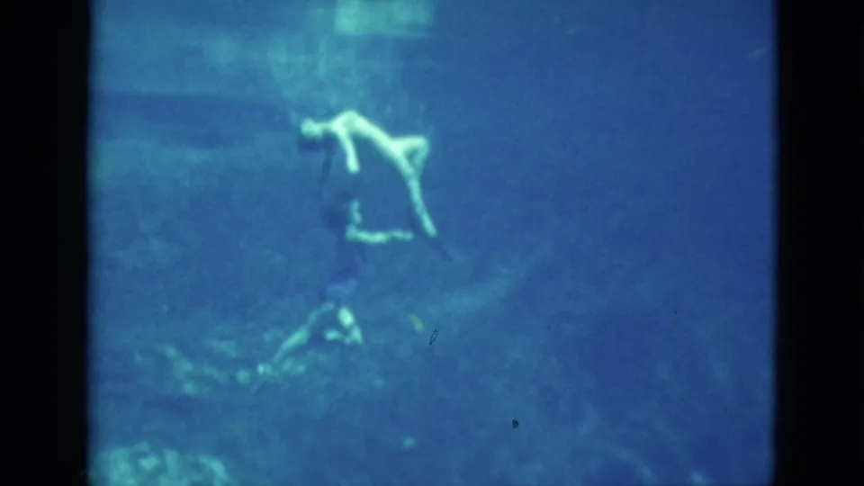 1952 Florida 8mm frame showing a swimmer farther from the camera, partly obscured by soft underwater haze.