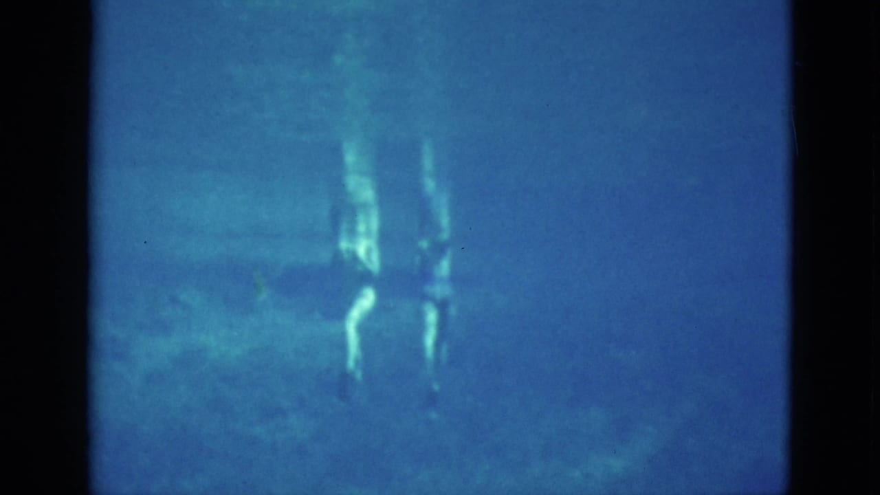 Blue underwater view with two faint human figures near the surface.
