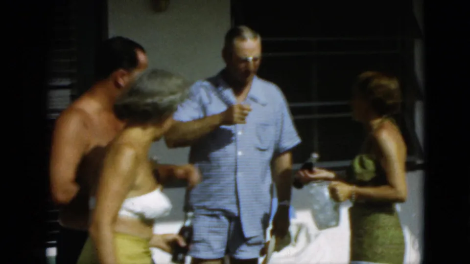 Several adults in 1952 Quebec patio footage cluster together, with swimwear, bottles, and a sunlit wall visible.