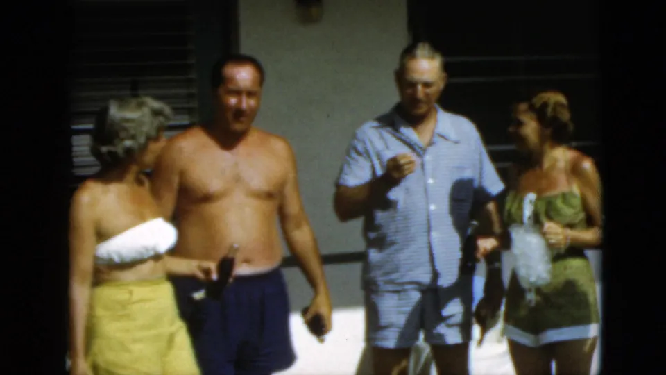 1952 Quebec frame of adults chatting outdoors, including a shirtless man, a man in blue, and a woman with a pitcher.