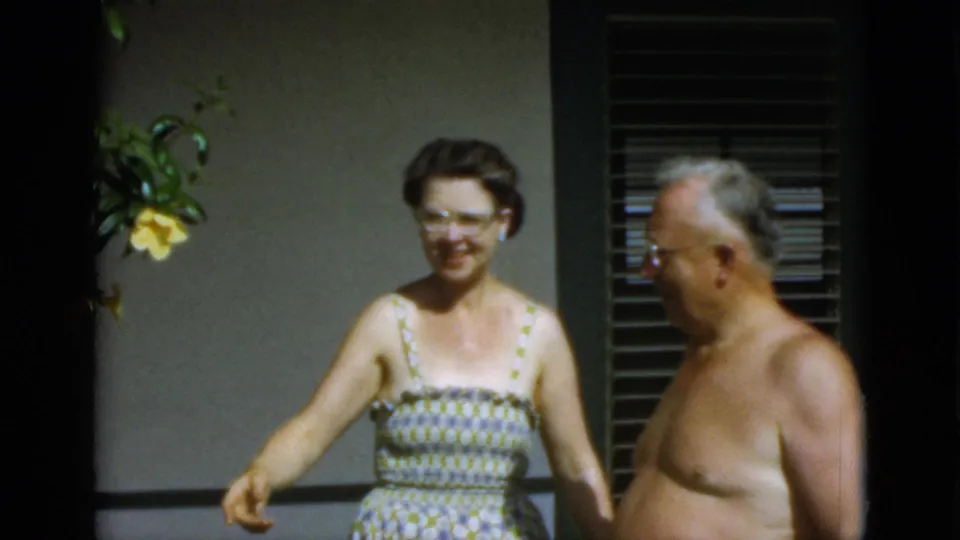 In the final frame, the woman gestures or steps forward as the shirtless man turns near a shuttered exterior wall in Quebec.
