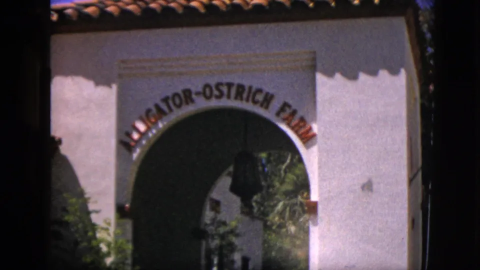 1952 Quebec home-movie view of the Alligator-Ostrich Farm entrance arch with white stucco wall and terracotta roof.
