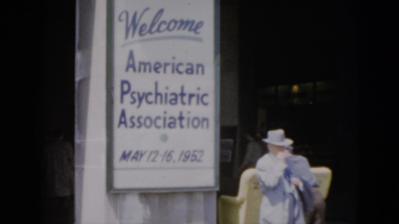 8mm color footage, Quebec 1952: large conference welcome sign for the American Psychiatric Association (May 12-16) with a woman in white hat and blue dress at a building entrance.