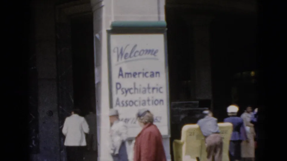 8mm color footage, Quebec 1952: APA conference welcome sign at a building entrance, with several attendees in period dress including a woman in a red jacket and a figure in white.