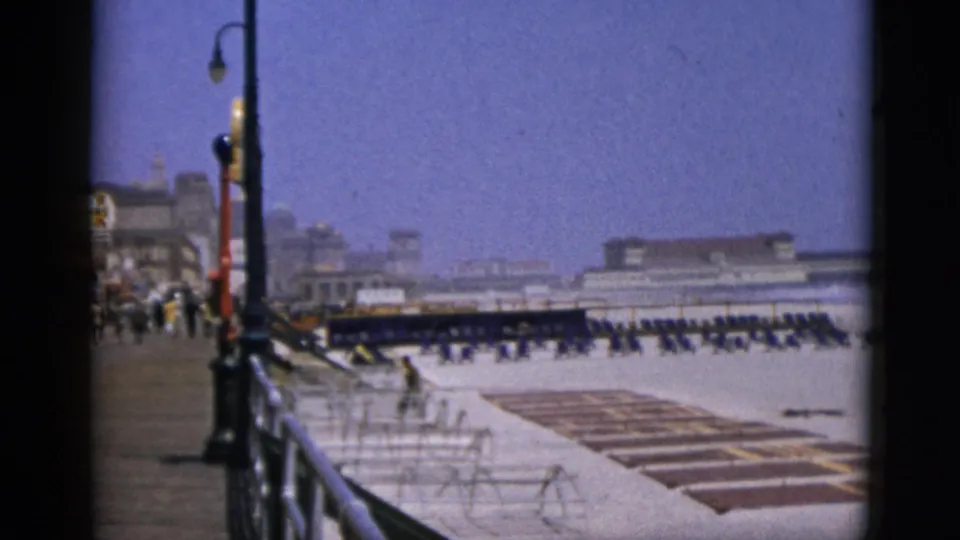 8mm home-movie frame, c. 1952, of a large open promenade or waterfront area with rows of outdoor seating and ornate street lamps; exact location not visually confirmed.