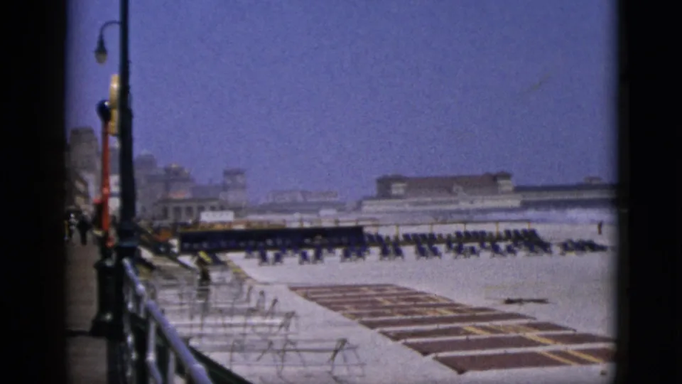 8mm home-movie frame, c. 1952, of a wide open outdoor leisure area with organized seating rows and globe-topped street lamps; location not visually confirmed.