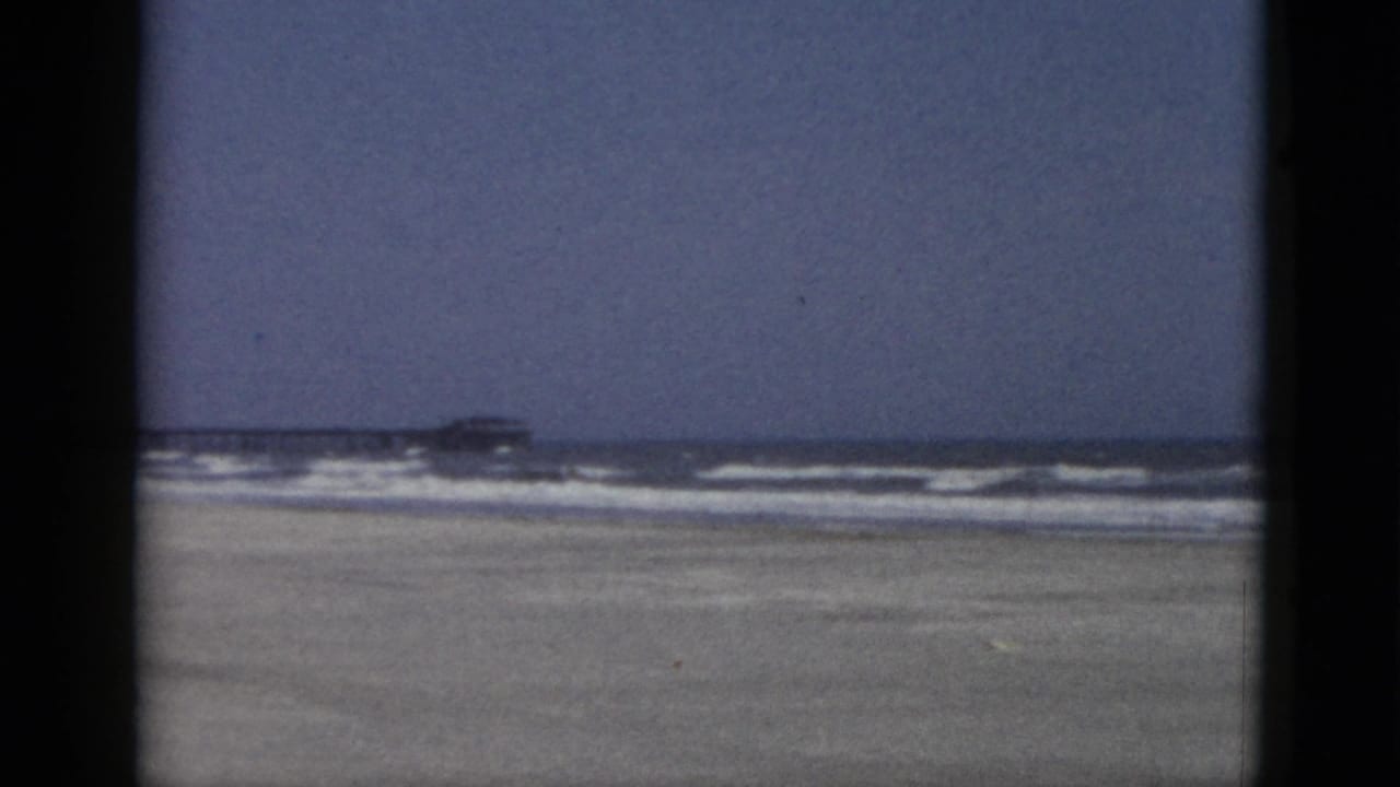 Wide 8mm color panorama of an empty sandy beach with surf at the horizon, Quebec, Canada, circa 1952.