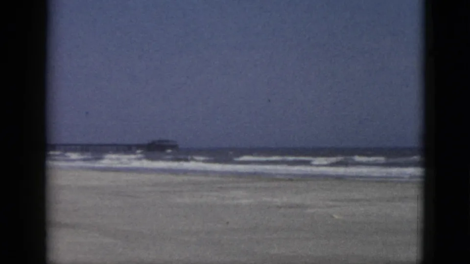 Wide 8mm color panorama of an empty sandy beach with surf at the horizon, Quebec, Canada, circa 1952.