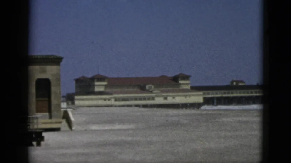 Closing 8mm color frame of the Quebec coastal scene, wooden kiosk and multi-section building with red-tiled roof, circa 1952.