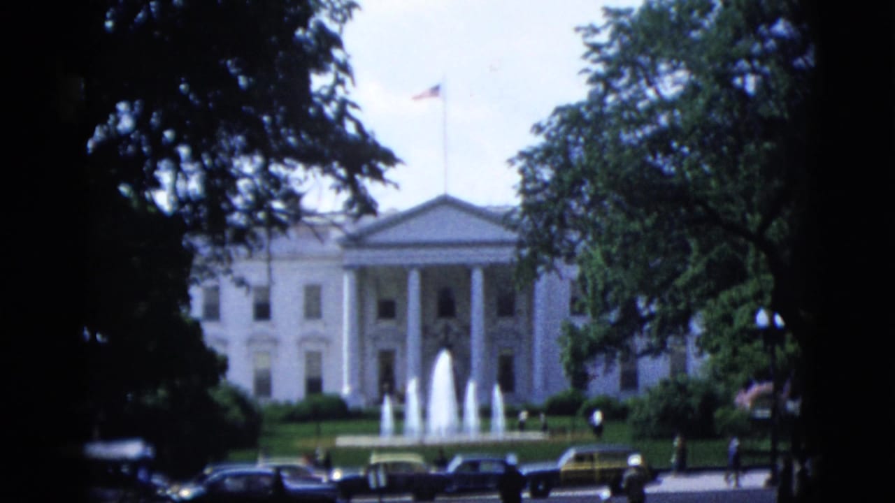 North facade of the White House, Washington DC, circa 1952, with active fountains, period automobiles, and an American flag flying over the roofline.