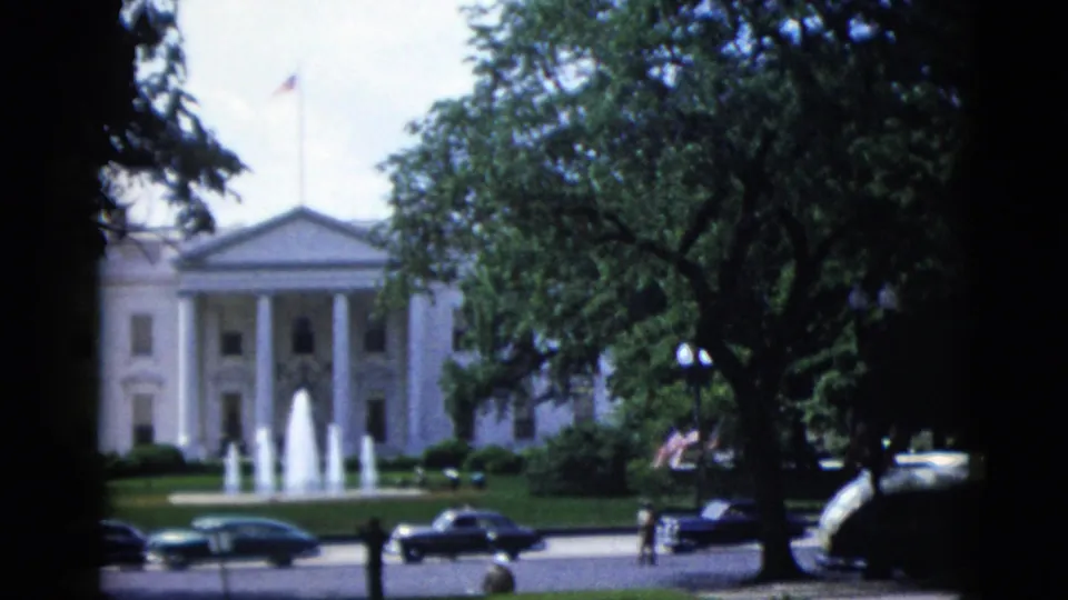 The White House North Portico in Washington DC, circa 1952, framed by mature trees with an active fountain and early-1950s automobiles on the street below.