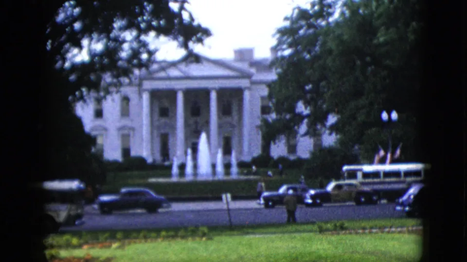 The White House North Portico, Washington DC, circa 1952, with active fountain, a passing bus, dark sedans, and a pedestrian figure near the street.