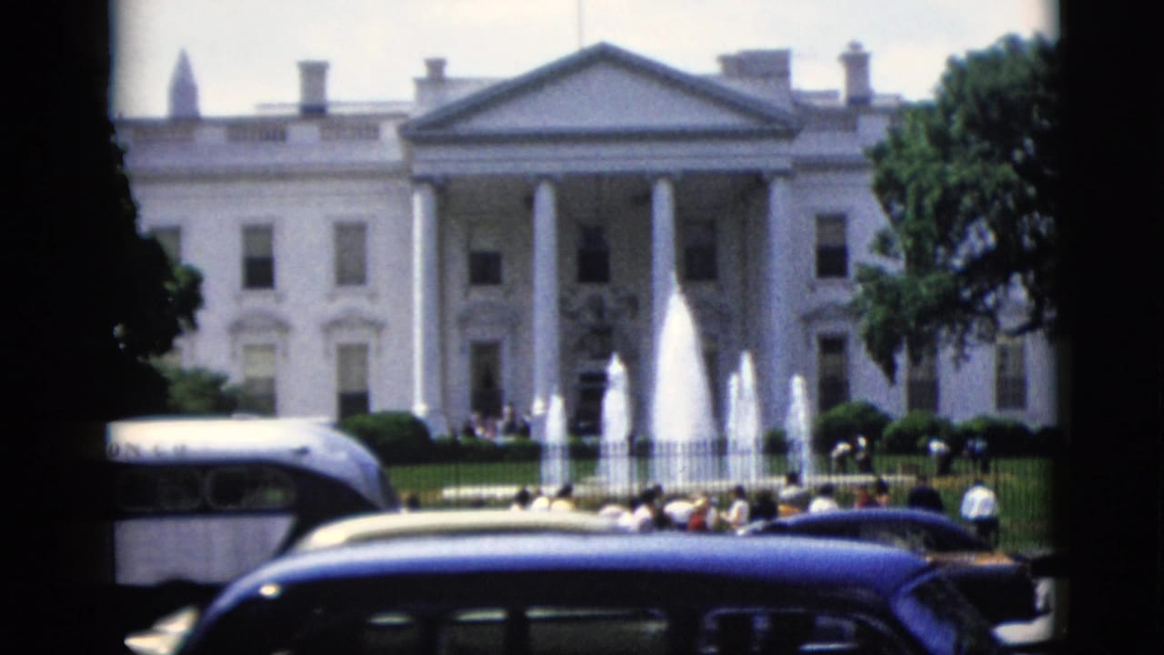 White House north facade, Washington DC, circa 1952 — central fountain jets, iron perimeter fence, and early-1950s dark sedans visible from street level in 8mm color film.