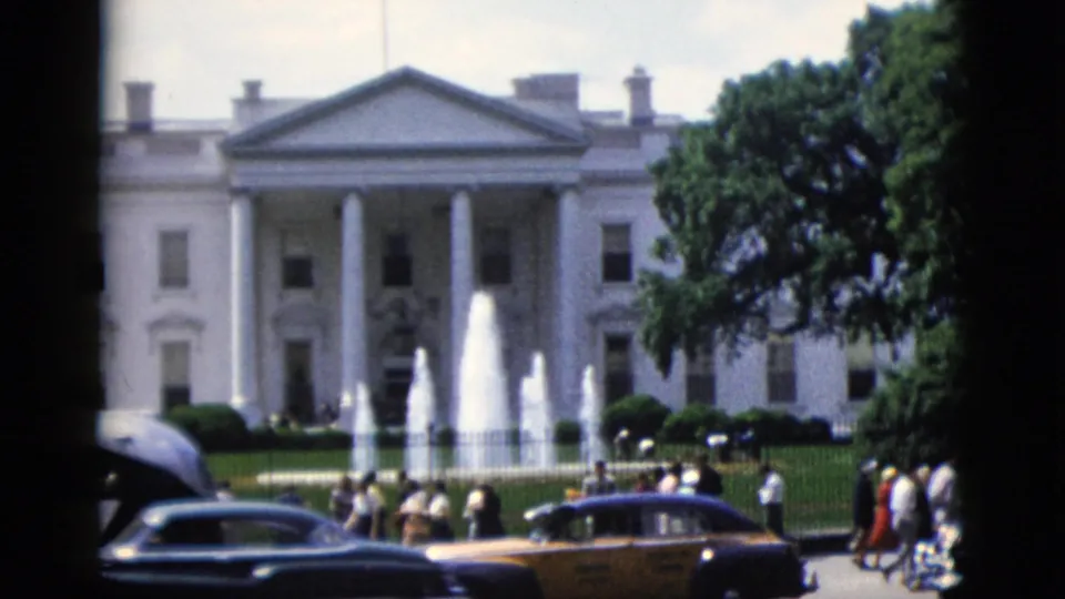 White House North Portico, Washington DC, circa 1952 — dark sedan foregrounded, bystanders near fence, multi-jet fountain behind.