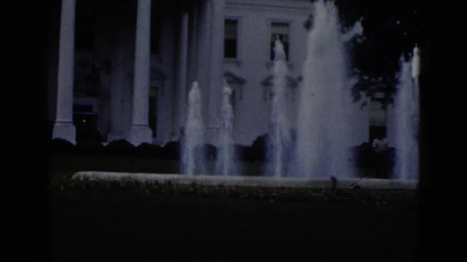 8mm home movie frame of White House north facade, Washington DC, circa 1952: foreground fountains, North Portico columns, lawn, and small figures near the grounds.