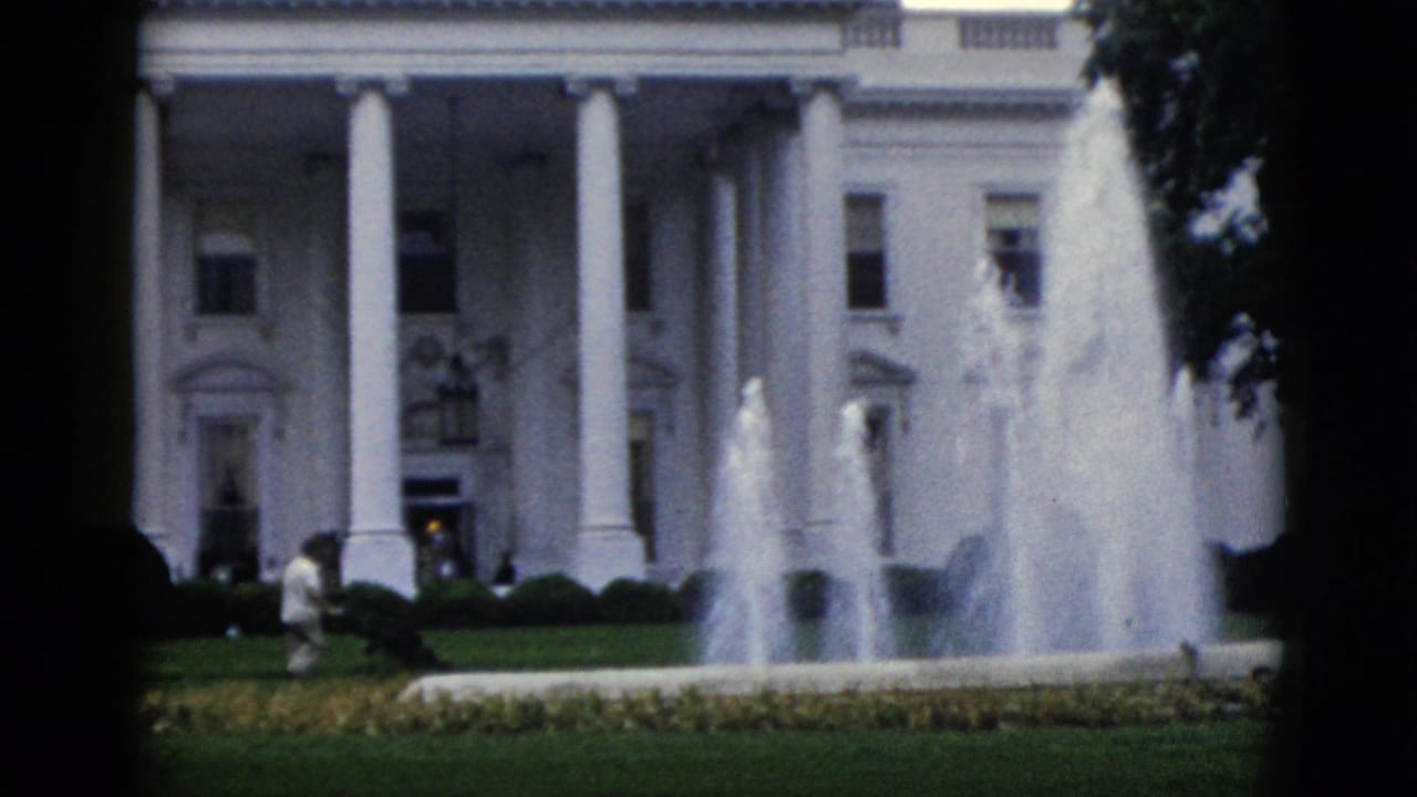 White House north portico, Washington DC, circa 1952 — active fountains, green lawn, and a distant visitor in light clothing near the hedges, on 8mm home-movie film.