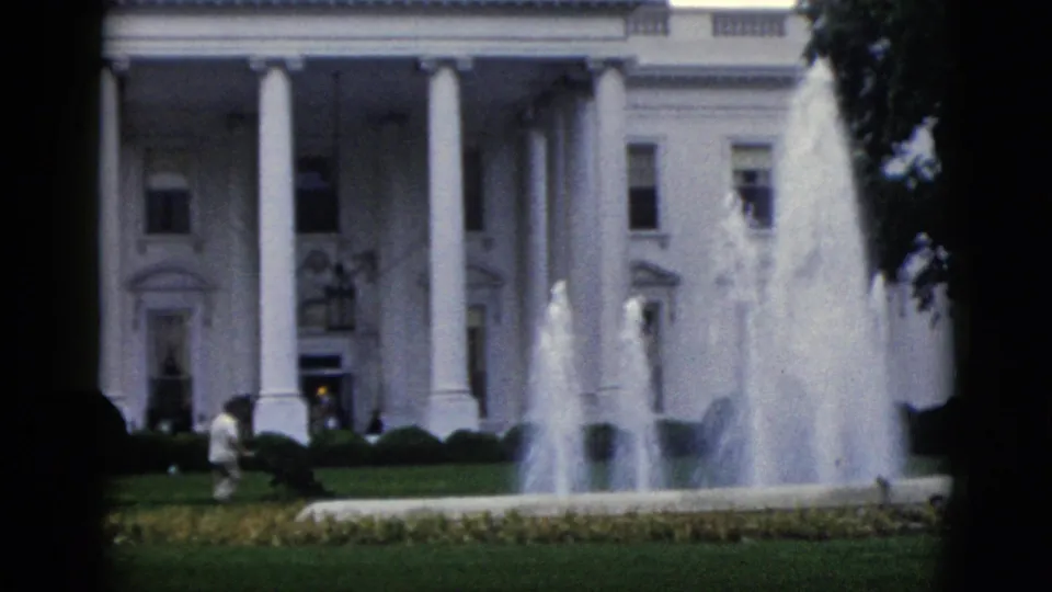 White House north portico, Washington DC, circa 1952 — active fountains, green lawn, and a distant visitor in light clothing near the hedges, on 8mm home-movie film.