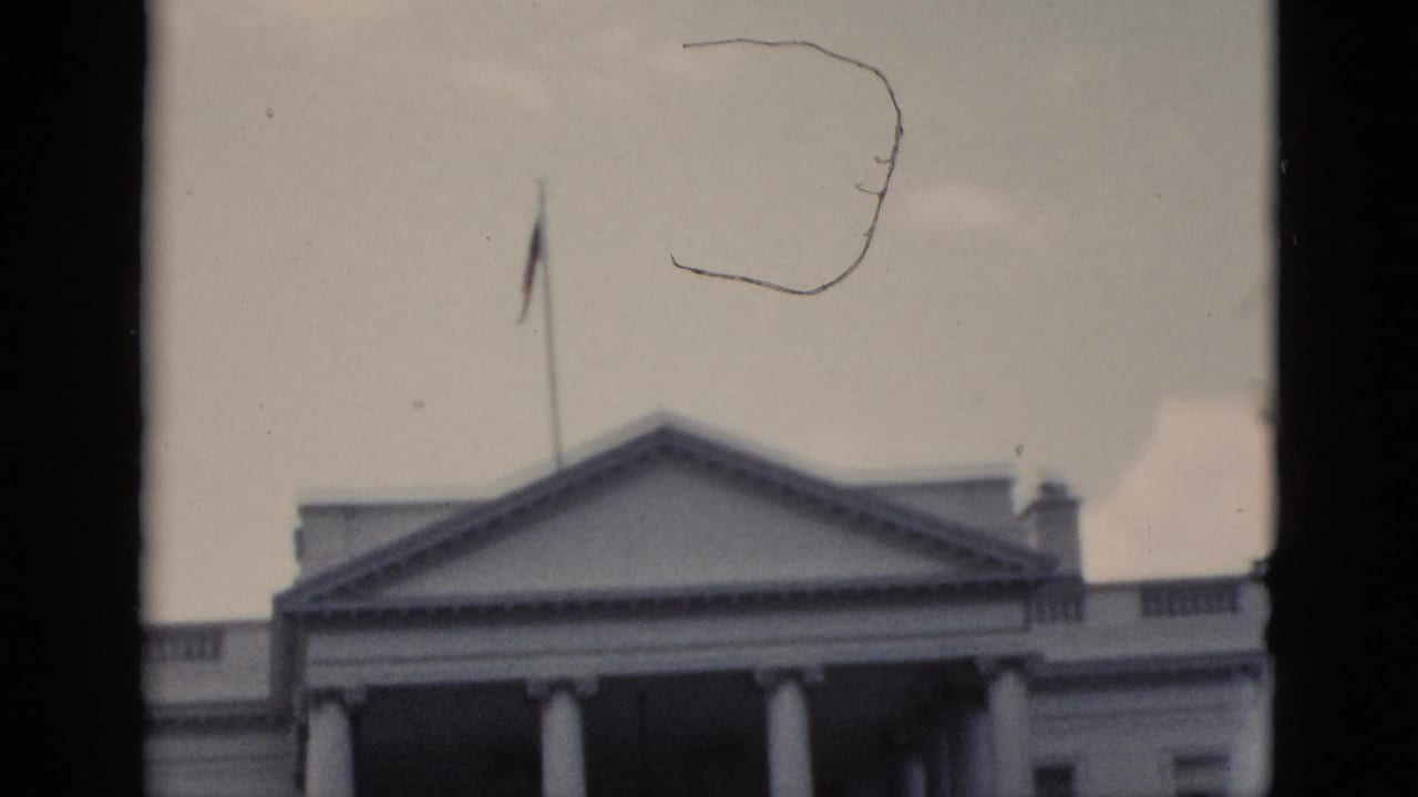 The White House North Portico with American flag on flagpole, filmed on 8mm in Washington DC circa 1952; film scratch artifact visible.