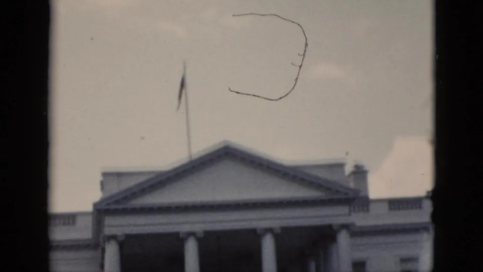 The White House North Portico with American flag on flagpole, filmed on 8mm in Washington DC circa 1952; film scratch artifact visible.