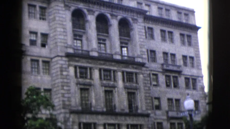 Upper floors of a large neoclassical stone building in Washington DC, circa 1952, with grouped arched windows and projecting cornice details.