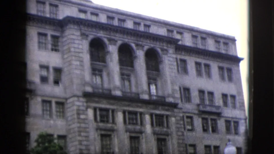 Multi-story neoclassical stone government building with arched upper windows, filmed on 8mm in Washington DC, circa 1952.