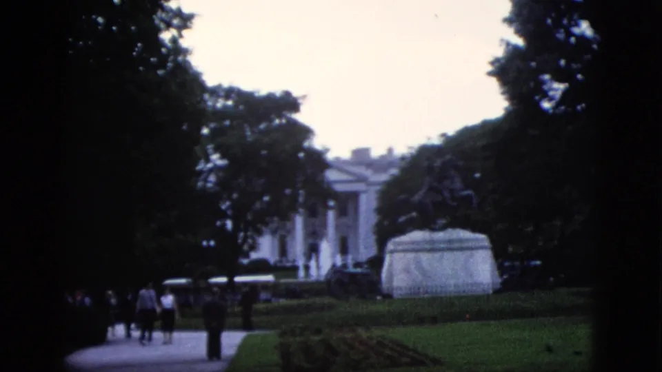 Tree-lined grounds with distant pedestrians and what appears to be a white columned building through trees, Washington DC, circa 1952.