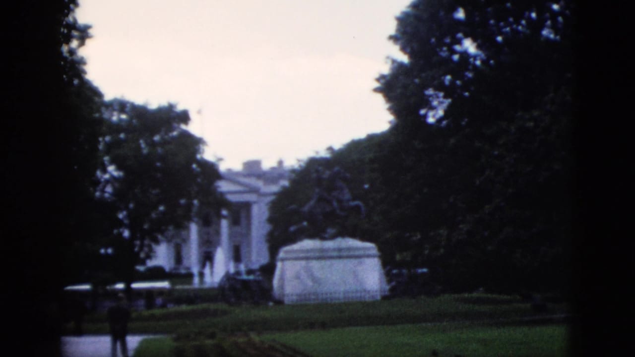 8mm home movie frame showing the White House north portico, equestrian statue pedestal, and a lone visitor on the path, Washington DC, circa 1952.