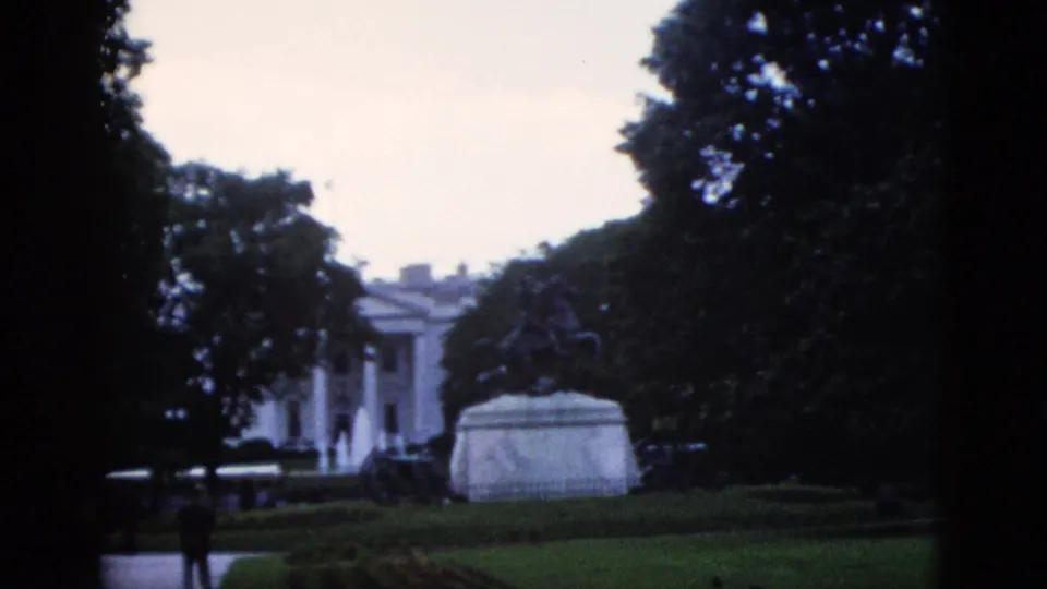 8mm home movie frame showing the White House north portico, equestrian statue pedestal, and a lone visitor on the path, Washington DC, circa 1952.