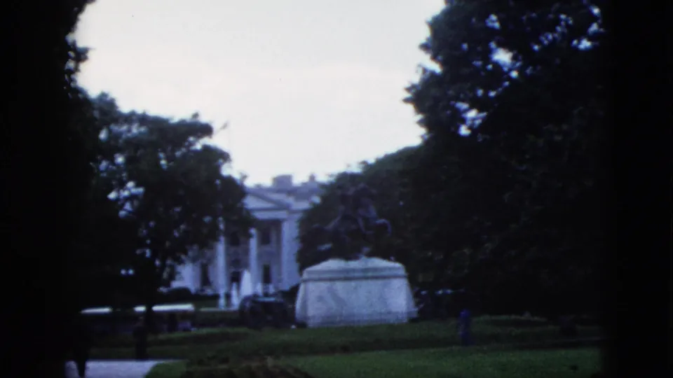 1952 8mm frame: wider shot of the White House with equestrian statue in the foreground, Washington DC, overcast sky and manicured lawn visible.